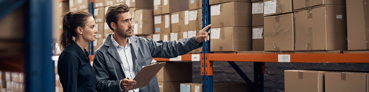 two supply chain professionals stand in a warehouse counting inventory