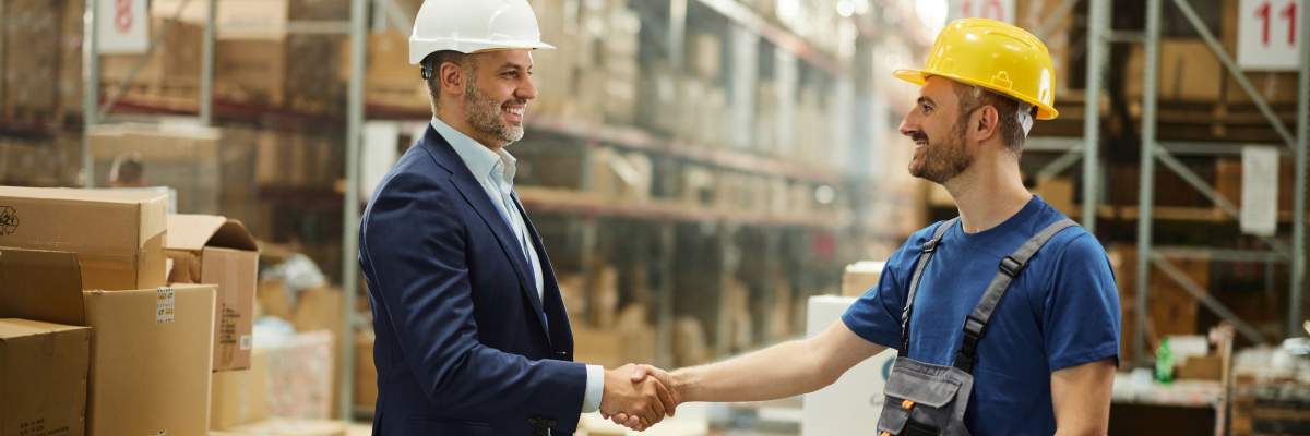 Two men shaking hands in a warehouse. 